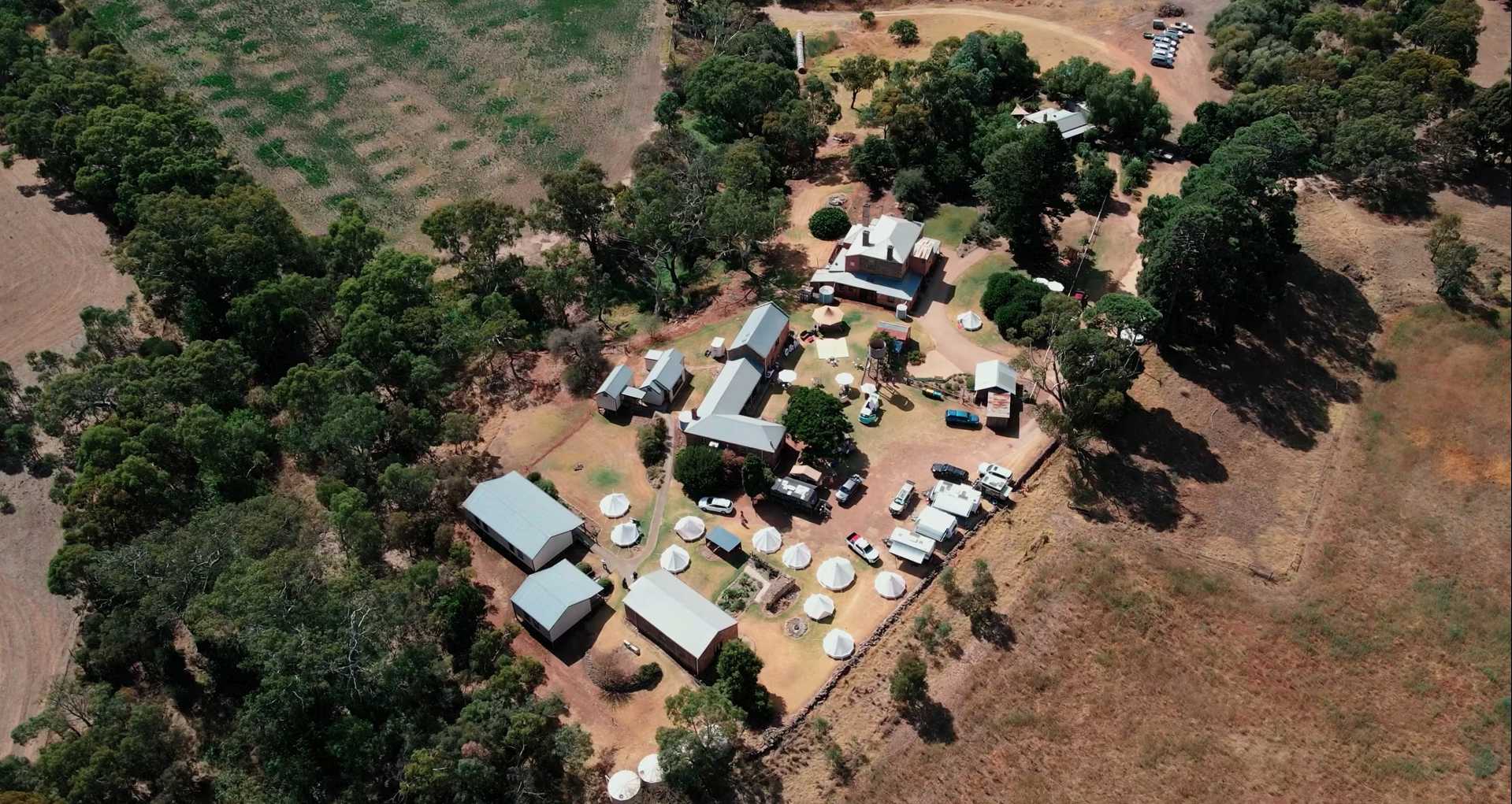 Aerial view of an outdoor wedding venue with marquees and tables among trees